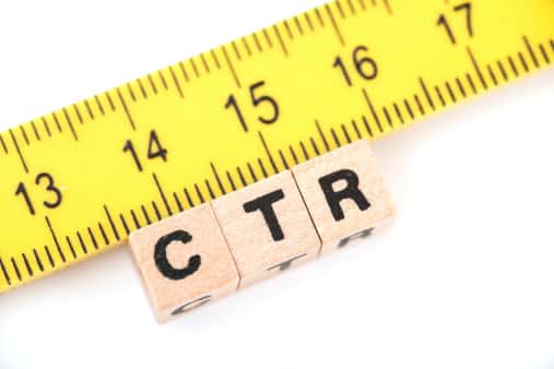 Fotografia de blocos de letras de madeira, os quais formam o termo "CTR". O mesmo está posicionado abaixo de uma régua amarela, o que indica a medição da métrica.