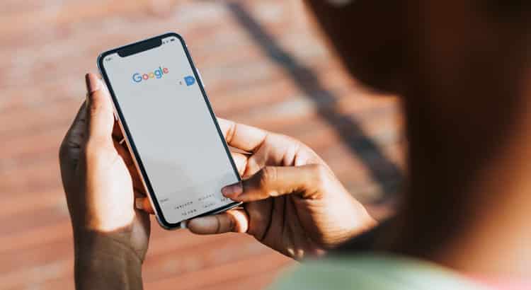 Homem jovem segurando um celular aberto na página de busca do Google.